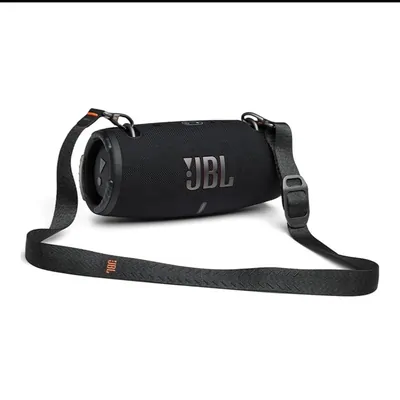 A black cylindrical portable speaker lying on its side with its woven carry strap unclipped beside it